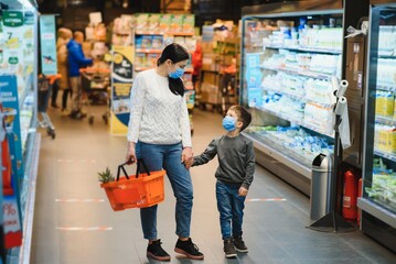 Obraz premium Mother and son are shopping at the grocery store. They wear masks during quarantine. Coronavirus Pandemic .COVED-19 Flash. The epidemic of the virus