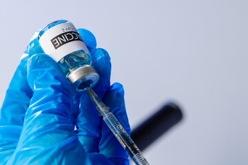 Doctor hands in blue gloves holding Sars-cov-2 vaccine vial