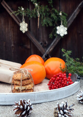 New year's composition: gifts, sweets, viburnum branches and orange persimmon on a wooden background, vertical frame-the concept of preparing and waiting for new year's holidays