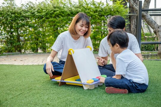 Asian family father mother and son playing with a chalkboard in the home garden. Focus mother image.