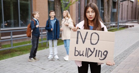 Portrait of young Caucasian schoolgirl standing outdoor with 