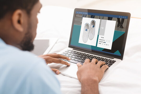 African American Man Doing Online Shopping Buying Shoes Sitting Indoors