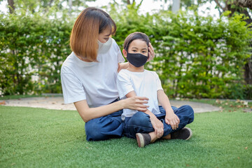 Asian mother wear a face mask to her son boy at home garden