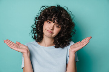 Unhappy beautiful curly girl posing and holding copyspace