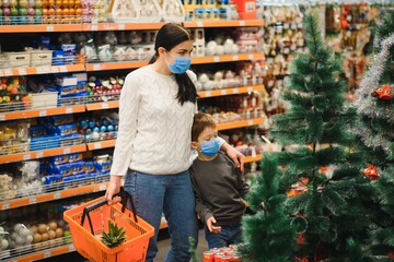 Mom and son in protective masks buy a Christmas tree during quarantine