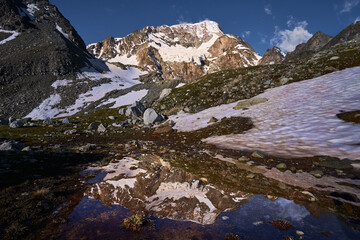 Fototapeta na wymiar reflection of Pigne d`Arolla mountain peak in a small high alpine lake. Arolla valley, Switzerland