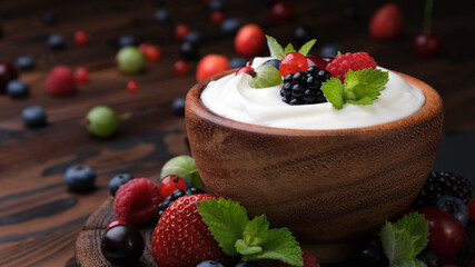 Yogurt with wild berries on dark wooden background