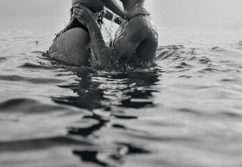 Black and white photo of a young boy and girl standing in the water. Love, passion, youth concept.