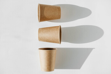 Three disposable paper cup with shadow from light on a white background. Top view. Copy, empty space for text
