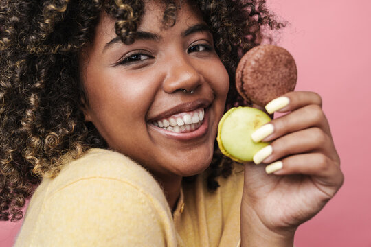Happy african american woman smiling while posing with macaroons