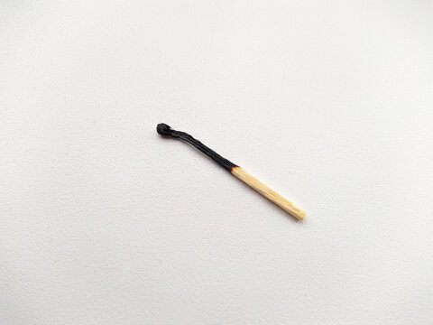 one charred wooden match on a white background