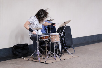 Male musician drummer playing a musical instrument at a public transport station