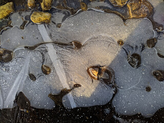 icy puddle together with small stones closeup photo
