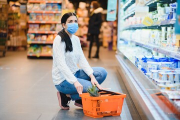Young woman with face mask walking through grocery store during COVID-19 pandemic.