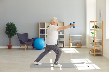 Active, sporty, healthy senior man doing fitness exercise with dumbbells at home