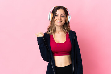 Young Romanian sport woman isolated on pink background pointing to the side to present a product