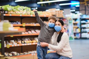 Young woman and her kid wearing protective face masks shop a food at a supermarket during the coronavirus epidemic or flu outbreak