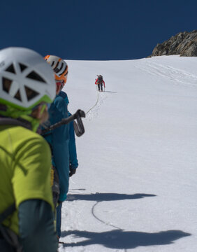 Mountaineers Looking At Their Friend Who Is Climbing Up A Snow Covered Steep Hill