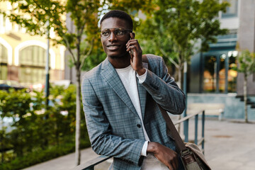 African american man talking on mobile phone while leaning on railing