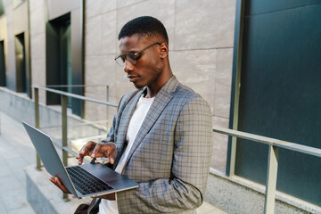Focused african american man smiling and using laptop