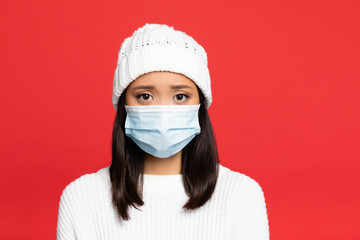 young asian woman in medical mask and hat isolated on red