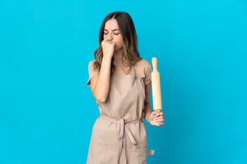 Fototapeta premium Young Romanian woman holding a rolling pin isolated on blue background having doubts