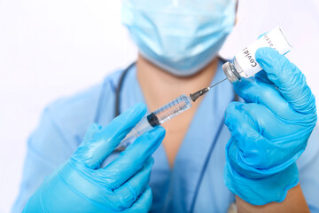 A gloved doctor fills a syringe with a virus vaccine.