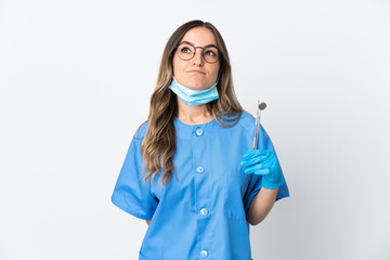 Woman Romanian dentist holding tools over isolated on pink background and looking up