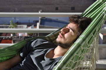 Chico joven durmiendo la siesta en una hamaca paraguaya - obrazy, fototapety, plakaty