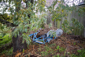 Abandoned blue bicycle with child seat next to a tree