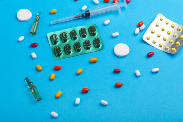 Scattered tape, blisters with medicine ampoules and syringe on a blue background.