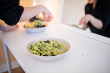 Bowl of guacamole sauce with olives on a white table