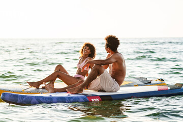 Obraz premium Young african couple talking on paddle boards