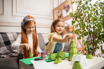Art. Two little children, girls together in creativity of the house. Happy kids make handmade toys for games or New Year celebration. Little caucasian models. Happy childhood, Christmas preparation.