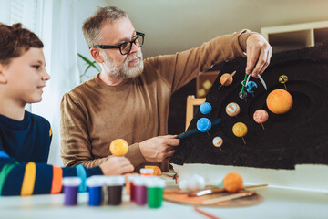 Happy school boy and his father making a solar system for a school science project at home © Mediteraneo