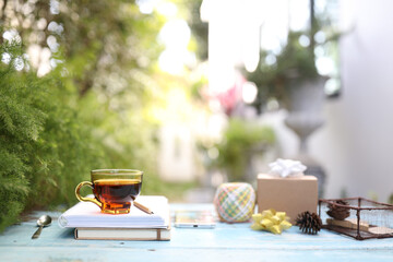 Tea cup with gidt box and notebooks on blue wooden table
