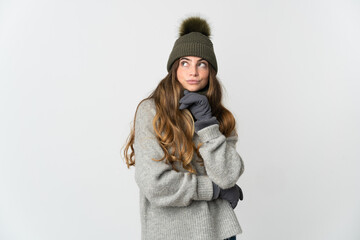Young caucasian woman with winter hat isolated on white background having doubts and thinking