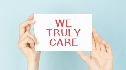Hands holding card sign with We Truly Care text message