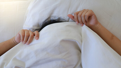 Young Woman Sleeping In Bed Playful hiding face under blanket while lying in cozy bed. Wake up in a good mood