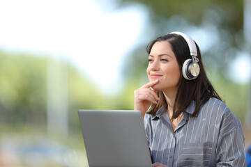 Woman with laptop and headphones thinks looking at side