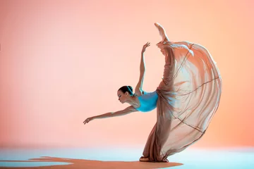 Gordijnen Ballerina in a light dress is dancing on colored background with backlight © Maria Moroz