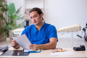 Young male doctor writing prescription in the clinic