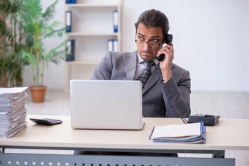 Fototapeta premium Young male employee talking by phone in the office