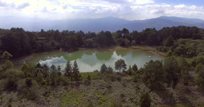 Pristine Green Guarne Lagoon in the Middle of the Woods near Medellin, Colombia on a Cloudy Day shot from in Smooth Travelling form Above