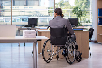 Young male employee in wheel-chair working in the office