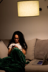 young latin woman working at home with laptop and phone