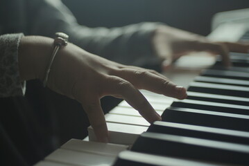 girl's hands on the piano keyboard close up