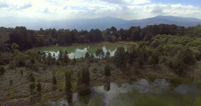 Pristine Green Guarne Lagoon in the Middle of the Woods near Medellin, Colombia on a Cloudy Day shot from in Smooth Travelling form Above