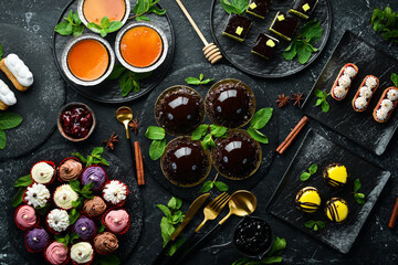 Set of sweets and desserts for coffee and tea on a black stone background. Top view. Rustic style.
