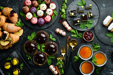 Set of sweets and desserts for coffee and tea on a black stone background. Top view. Rustic style.